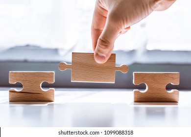 Hand holding wooden jigsaw puzzle and blank space  There is matching puzzle next to it  The concept solving problems  all problems can be solved  connection 