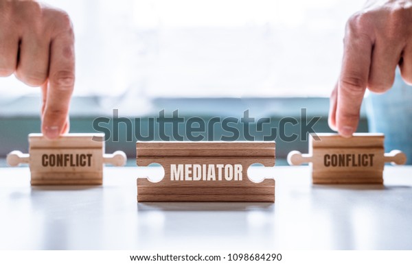 Hand\
holding a wooden jigsaw puzzle with conflict and Mediator word.\
There is a matching puzzle next to it. The concept of solving\
problems, all problems can be solved,\
connection.