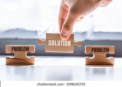Hand holding wooden puzzle and the word solution  There is matching puzzle next to it and the word problem  The concept solving problems  all problems can be solved 