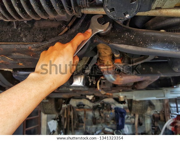 Hand holding  wrench fixing\
the car parts. Automotive, car machine, vehicle equipment\
concept.