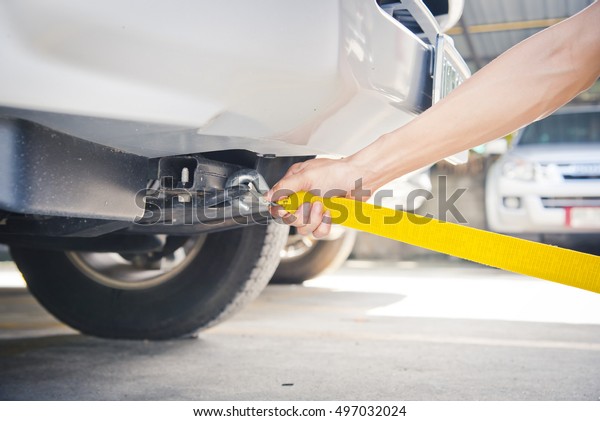Hand\
holding yellow car towing strap with car, car\
towing