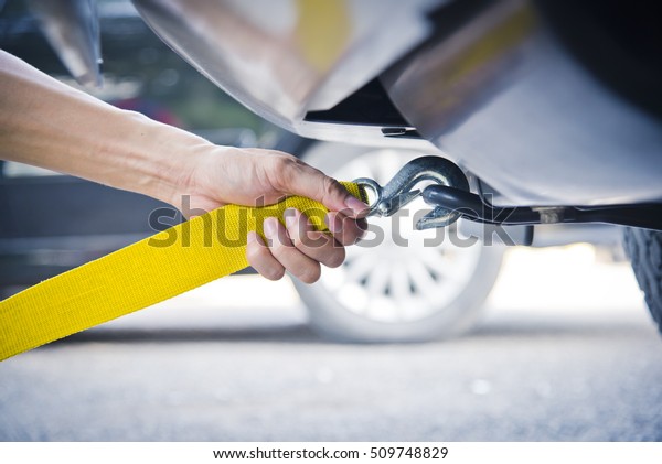 Hand holding yellow car towing strap with car, car\
towing, towing rope\
