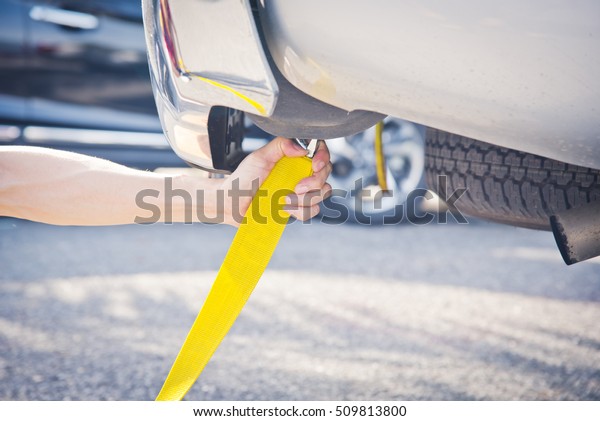Hand holding yellow car towing strap with car, car\
towing, towing rope 