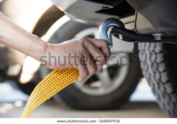 Hand holding yellow car towing strap with car, car\
towing, towing rope 