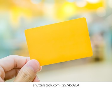Hand holding yellow dummy card (to be replaced with your own) in the elegance atmosphere