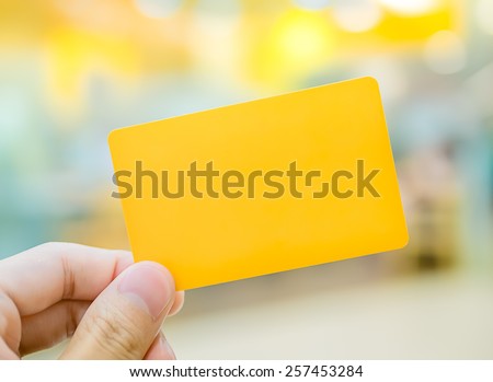 Hand holding yellow dummy card (to be replaced with your own) in the elegance atmosphere