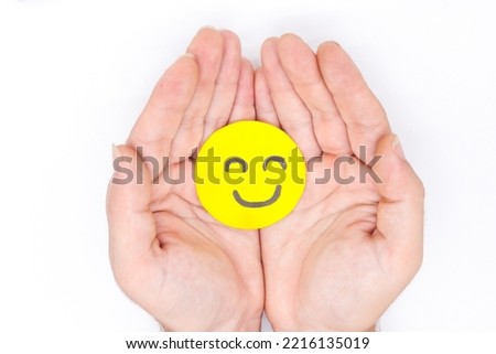hand holding yellow paper happy faces on a white background. Concept of positivism, optimistic, happy, well-being, joy, help,