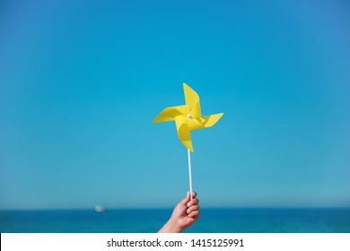 Hand Holding Yellow Pinwheel In The Sea