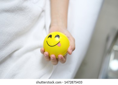 Hand Holding Yellow Smiley Stress Ball While Collecting Blood In Clinic