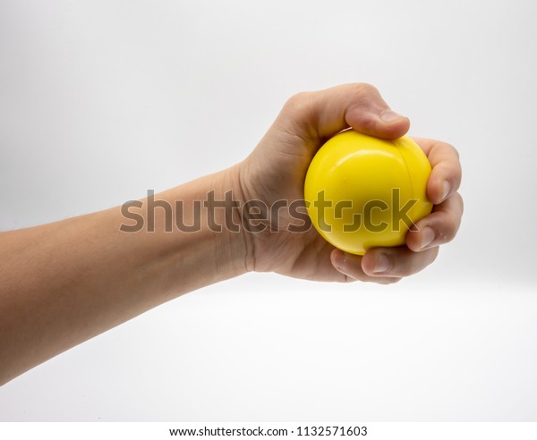 Hand holding yellow stress ball isolated on\
white background.