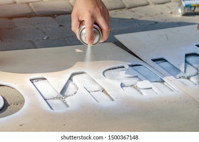 Hand holds an aerosol spray can, puts the image on the asphalt through a stencil - Powered by Shutterstock