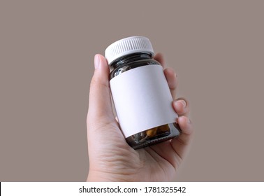 Hand  holds the amber glass drug bottle to show or see the label. There is copy space on the label. The bottle use for pills, supplements, vitamins, capsules.