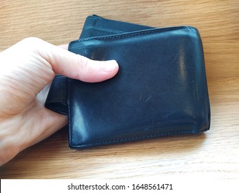 Hand Holds Black Leather And Thick Wallet With Money