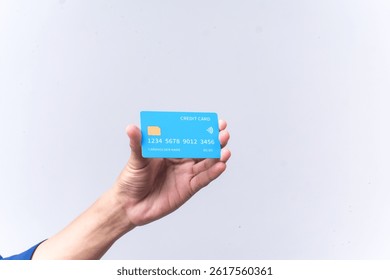 A hand holds a blue credit card against a light gray background. The card shows the words 'CREDIT CARD', a four digit number sequence, and a contactless payment symbol.