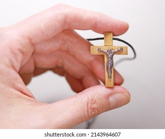 Hand holds a catholic cross with the figure of Jesus Christ. Christian symbol of faith, prayer and spirituality. Wooden Catholic Cross.