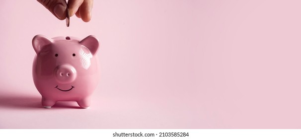 The hand holds a coin and puts it in a piggy bank to preserve wealth, savings and financial success.