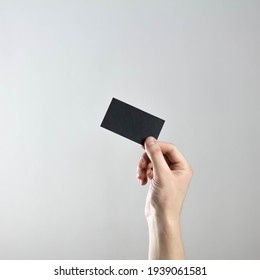 The hand holds an empty black business card. A clean flyer in your hands. For your text. Isolated on a gray background.