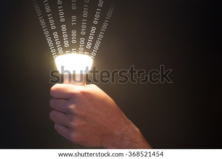 Hand holds a glowing bulb emitting data
