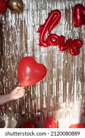 A Hand Holds A Heart Balloon On The Background Of Golden Tear Drop And The Words Love. Congratulations On Valentine's Day.