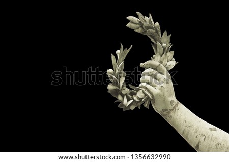 Hand holds a laurel wreath - bronze statue on black background - Success and fame concept image - image with copy space