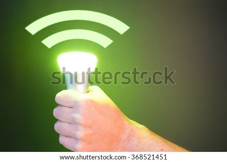 Hand holds a Lifi symbol with glowing bulb combined with wifi symbol