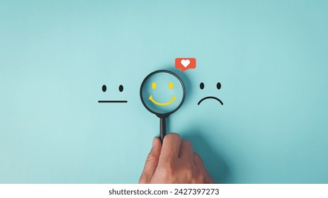 A hand holds a magnifying glass over a smile face with a heart, symbolizing the search for positivity among neutral and sad expressions in customer service satisfaction feedback concept. - Powered by Shutterstock