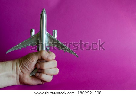 A hand holds a model of a silver airplane. The male hand holds the plane tightly. Airplane hijacking concept. Combating International Terrorism. Selective focus.
