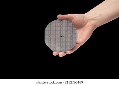 A Hand Holds A Multilayer Semiconductor Silicon Wafer With A Microcircuit Chip Of A Powerful Darlington Transistor Isolated On A Black Background.