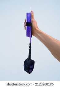 Hand Holds New Purple Leash For Surfing On White Background.