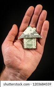 Hand Holds Origami Paper Money House For Real Estate And Housing Market Concept