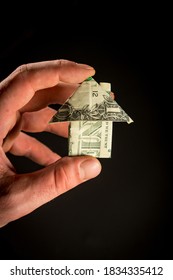 Hand Holds Origami Paper Money House For Real Estate And Housing Market Concept