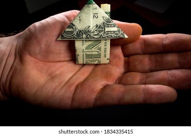 Hand Holds Origami Paper Money House For Real Estate And Housing Market Concept