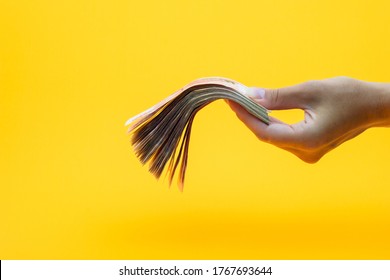 Hand Holds Out A Wad Of Money, Yellow Background