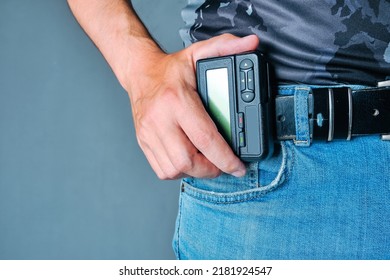 Hand holds pager weighing on belt jeans