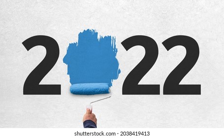 hand holds paint roller and painting 2022 year on wall. happy new year 2022  - Shutterstock ID 2038419413