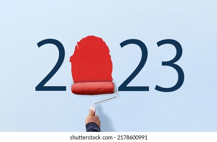 hand holds paint roller and painting 2023 year on wall. happy new year 2023.  - Shutterstock ID 2178600991