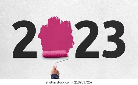 hand holds paint roller and painting 2023 year on wall. happy new year 2023  - Shutterstock ID 2189837269