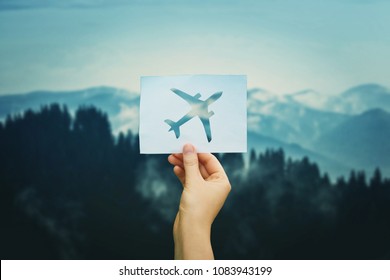 Hand holds a paper with plane icon over silent nature background. Love travel concept. Flight restrictions due coronavirus COVID-19 pandemic outbreak. Only charter flight allowed. Quarantine concept.
