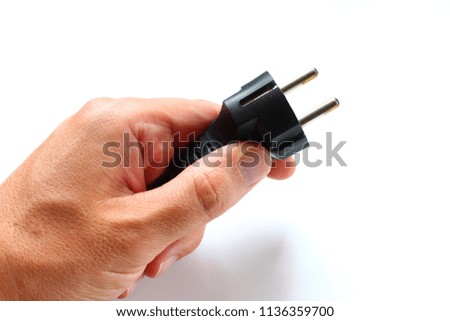 The hand holds a power plug close-up