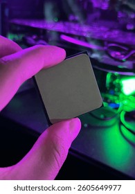 A hand holds a processor with vibrant lights glowing in the techy background.
