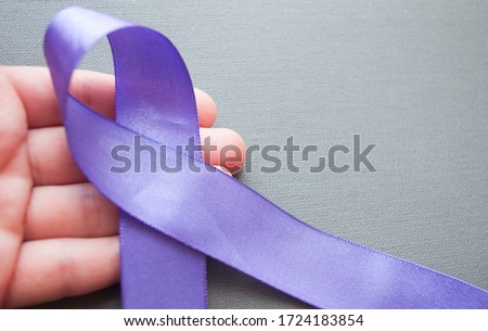 hand holds purple awareness ribbon. World Lupus Day. Autoimmune disease. Immune System Disorders. May Lupus Awareness Month.