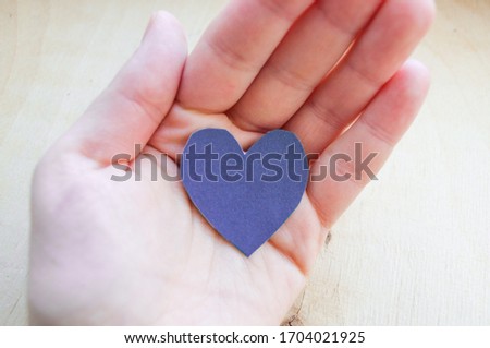 Hand holds a purple heart.
Expression of understanding and compassionate love. Love and caring. The concept of parents and children. Military medal for wounded soldiers.