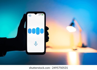  A hand holds a smartphone displaying a waveform graphic representing an AI responding to a voice query. The background is illuminated by blue and warm LED lights - Powered by Shutterstock