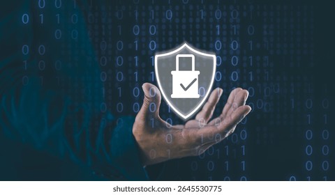 A hand holds a transparent shield icon with a download arrow and checkmark, symbolizing cybersecurity and data protection amidst binary code.