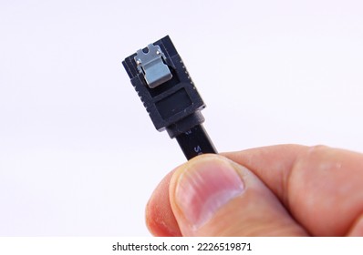 A hand holds a wire with ESATA connectors on a white background close-up.Soft focus.