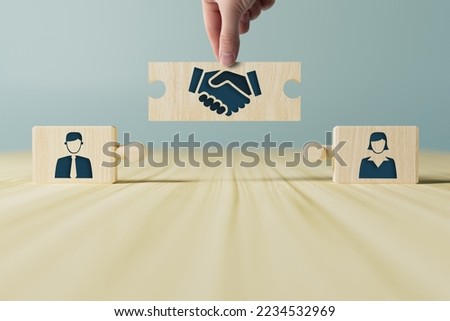 The hand holds wooden wooden blocks with icons of a woman and a man and shaking hands in the act of consent. The concept of divorce, agreement, mediation, the role of the mediator.