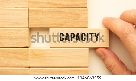 Hand holds a wooden cube with the text CAPACITY. Positive thinking concept