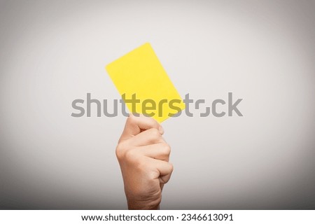 the hand holds a yellow card as an attribute of punishment