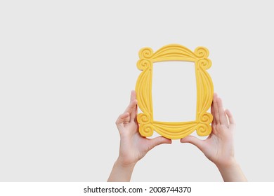 a hand holds a yellow frame from the TV series friends - Shutterstock ID 2008744370