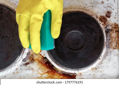 hand in household glove cleaning grease and dirt from kitchen stove